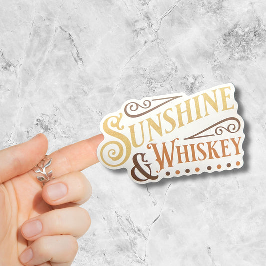 sunshine and whiskey sticker stuck to a finget on a marble background
