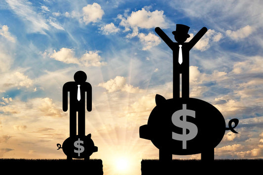 photo shows a sunset with a sillouette drawing of a man standing on a small piggy bank, appearing ashamed, next to a man on a large piggy bank, his hands proudly in the air 