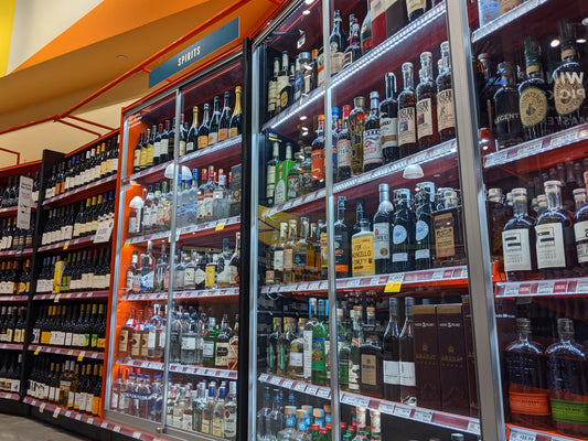 A liqour store aisle with multiple full shelves of whiskey 