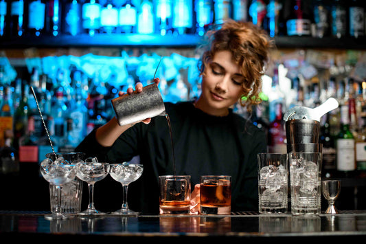 female bartender pouring a whiskey cocktail over a large format ice cube