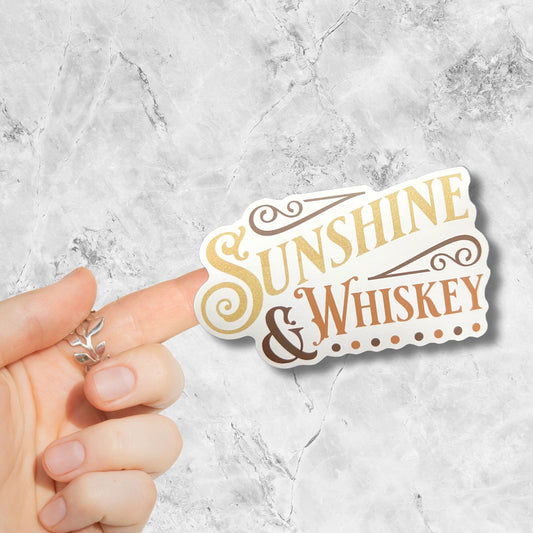 sunshine and whiskey sticker stuck to a finget on a marble background 