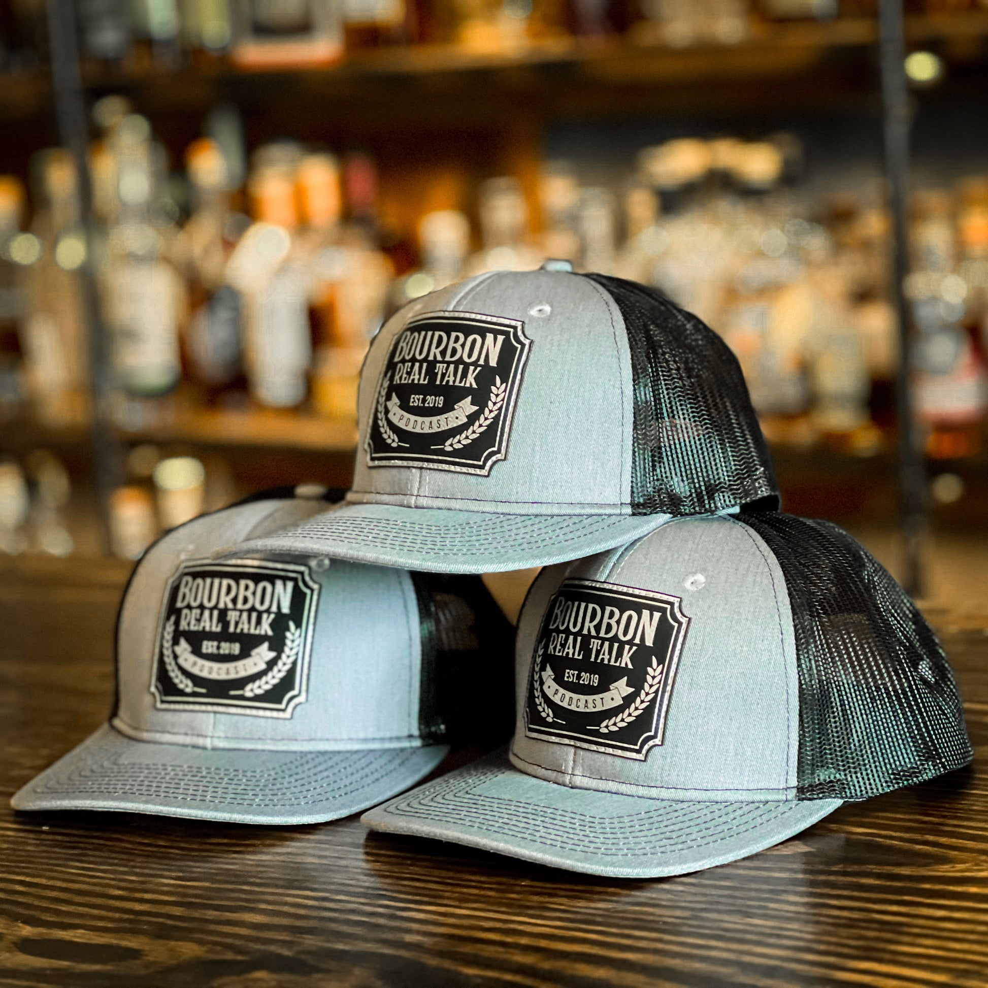 photo shows a stack of three structured trucker hats with a laser etched leaher patch, shown from side.