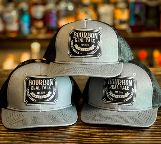 photo shows a stack of three structured trucker hats with a laser etched leaher patch. 