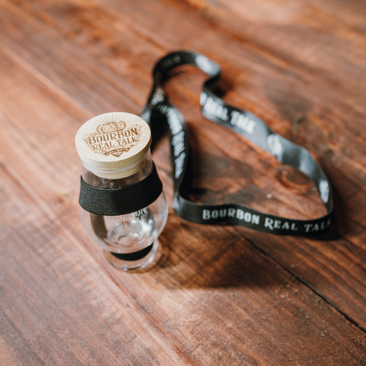 photo of a Bourbon Real Talk Lanyard holding a tasting glass that has a lid on it. 