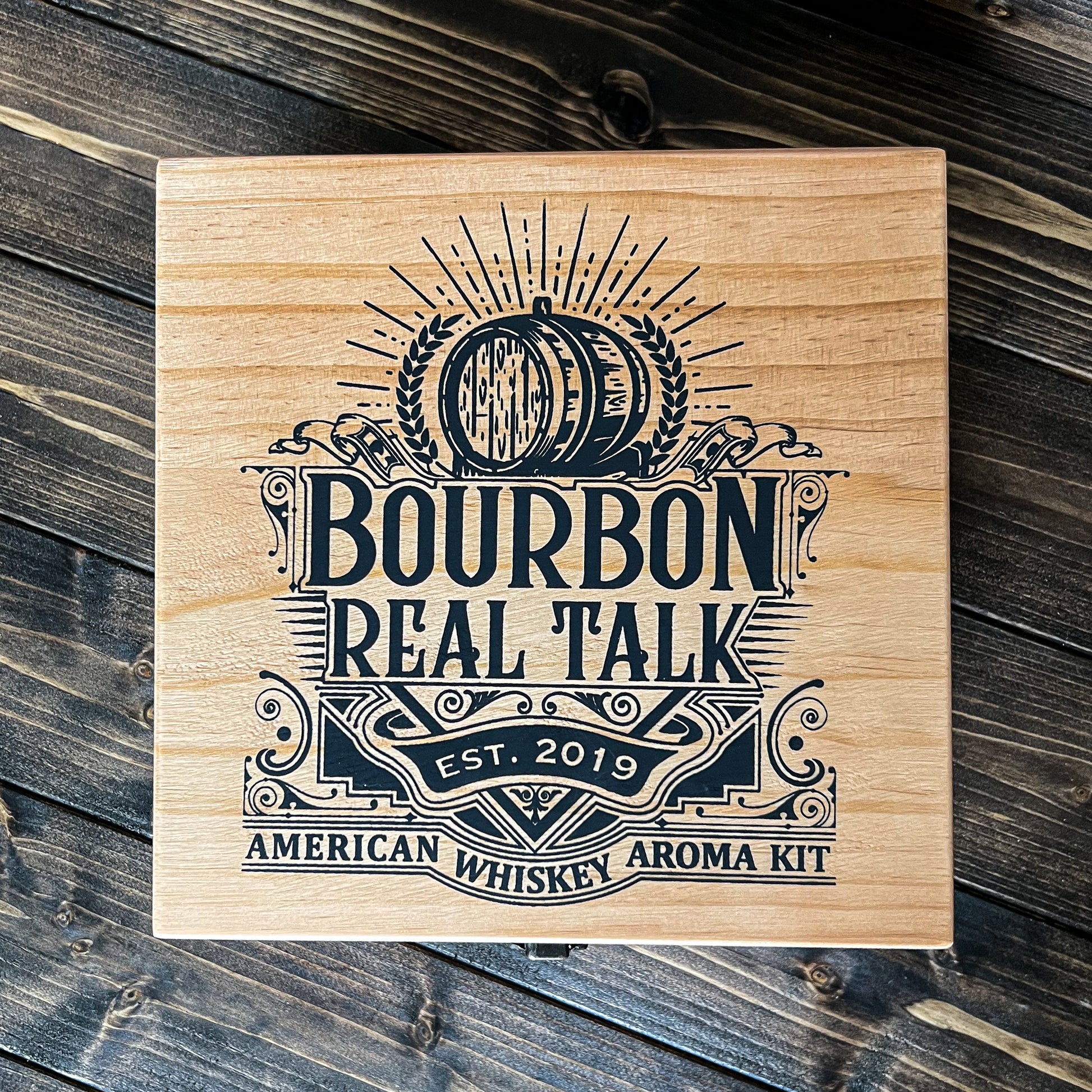 Top photo of the American Whiskey Aroma Kit, with the logo in black paint on light wood box