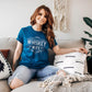 Woman with red hair, sitting on a couch with a Dark Teal Whiskey Wife Shirt on