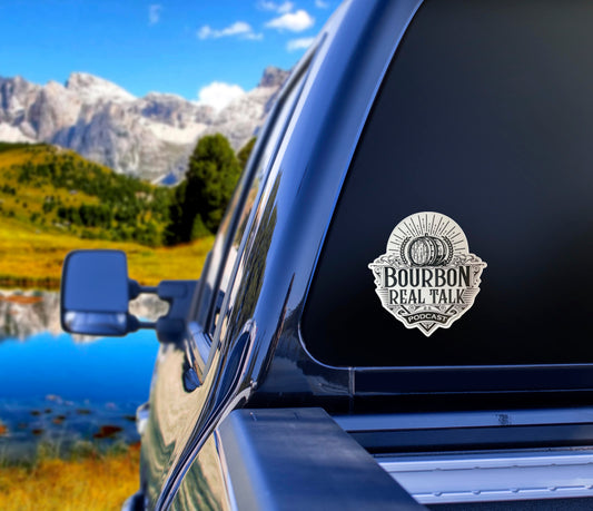 Bourbon Real Talk Matte Vinyl sticker on the rear window of a blue pickup truck facing a mountain scene
